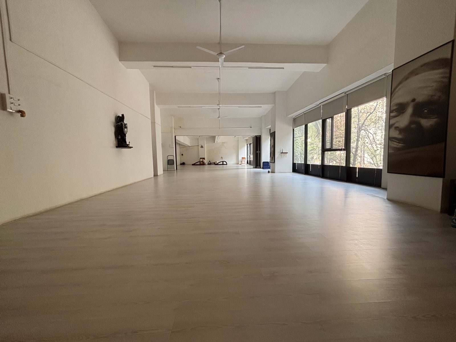 The shala practice hall with tall windows and a wooden floor
